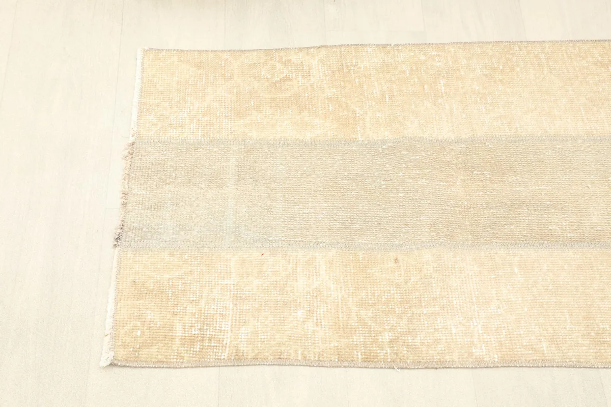 Angled shot from above, showing the full length and width of the beige vintage rug.