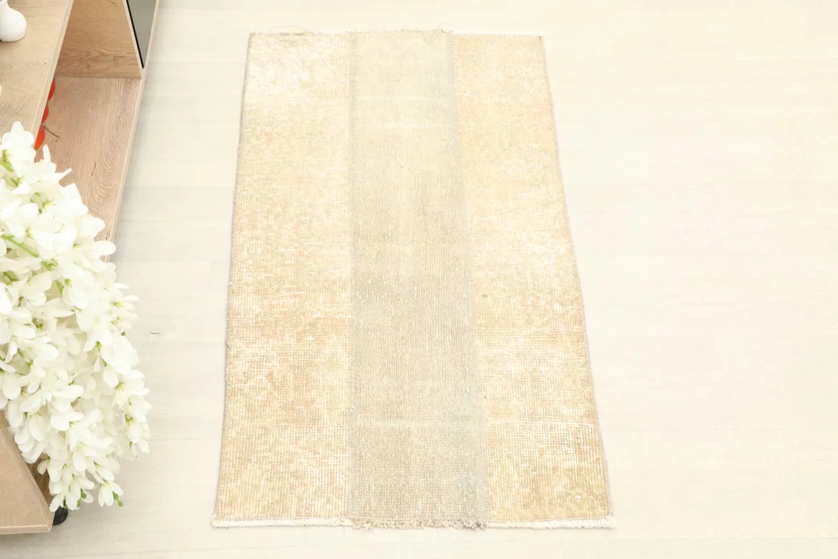 Overhead view of the beige and tan vintage rug, showing its faded panel design.