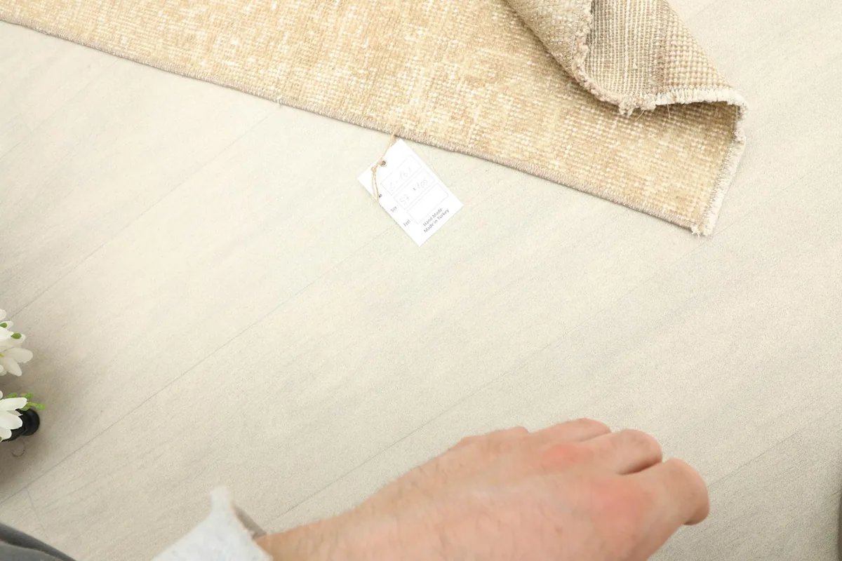 A partial view of the rug with a hand nearby, indicating its mini size.