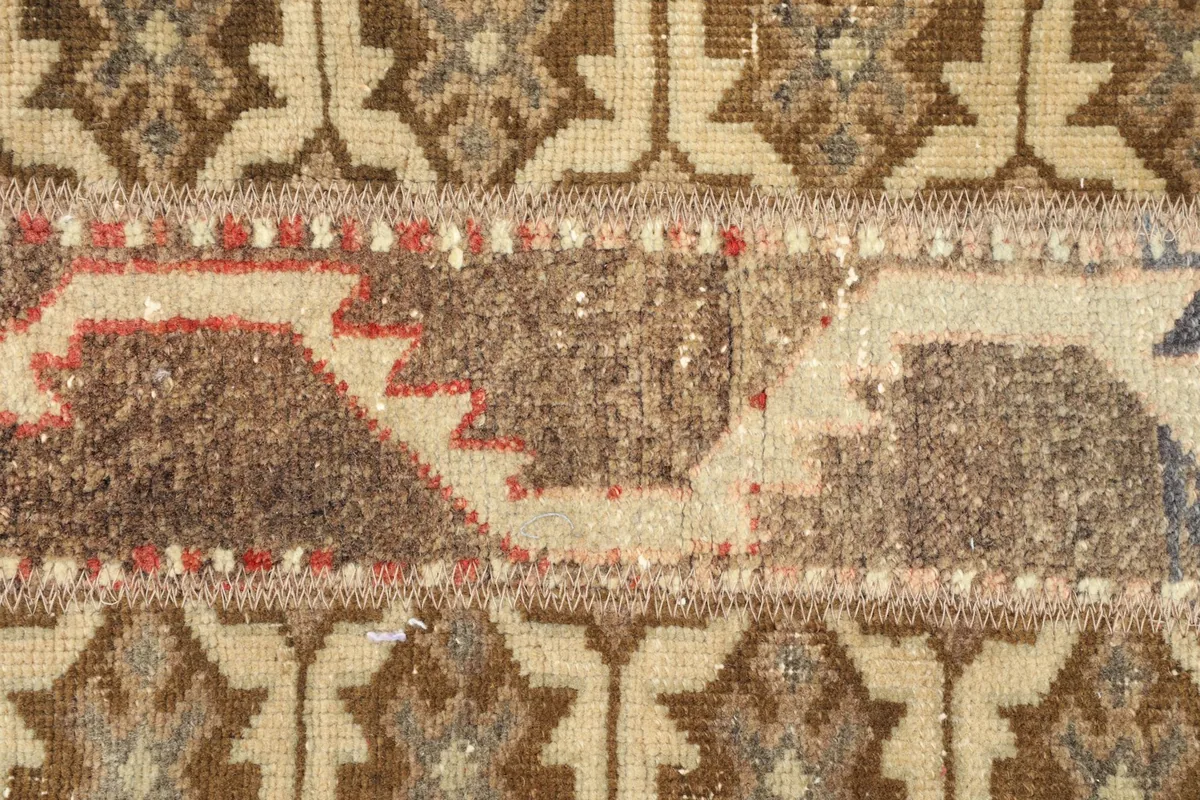 Extreme close-up of the rug's central design, revealing the hand-knotted wool pile and intricate tribal patterns.