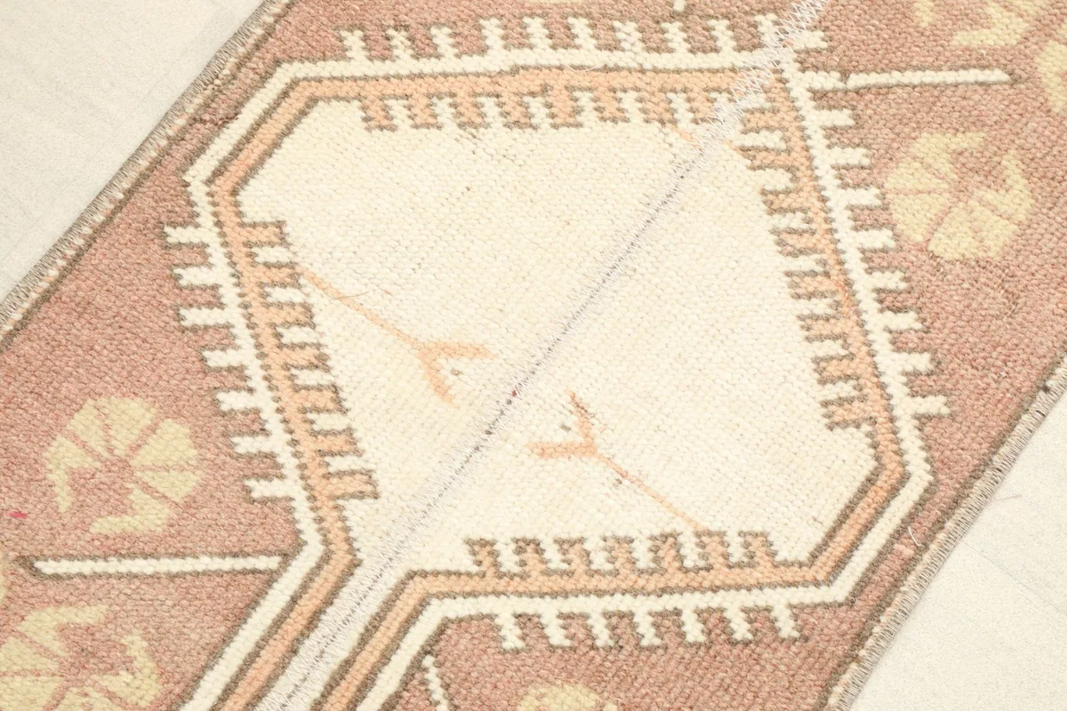Detailed view of the central ivory geometric medallion and surrounding tan and rose motifs.