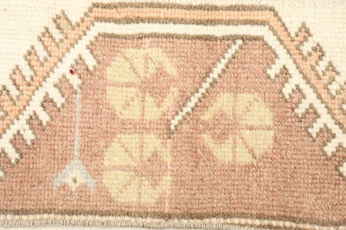 Close-up of the rug's wool pile, showing the rose and tan colors and tribal patterns.