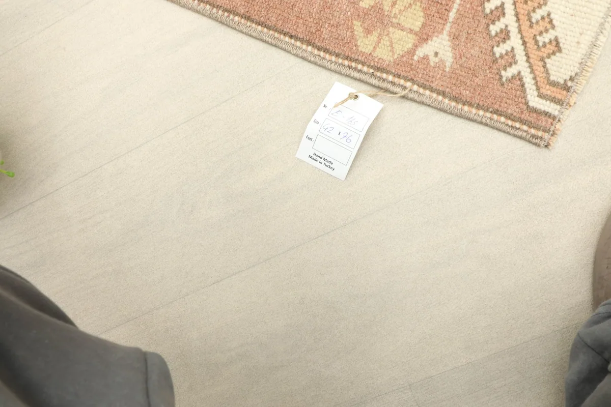 Partial view of the rug with a tag, providing a sense of scale and context in a room setting.