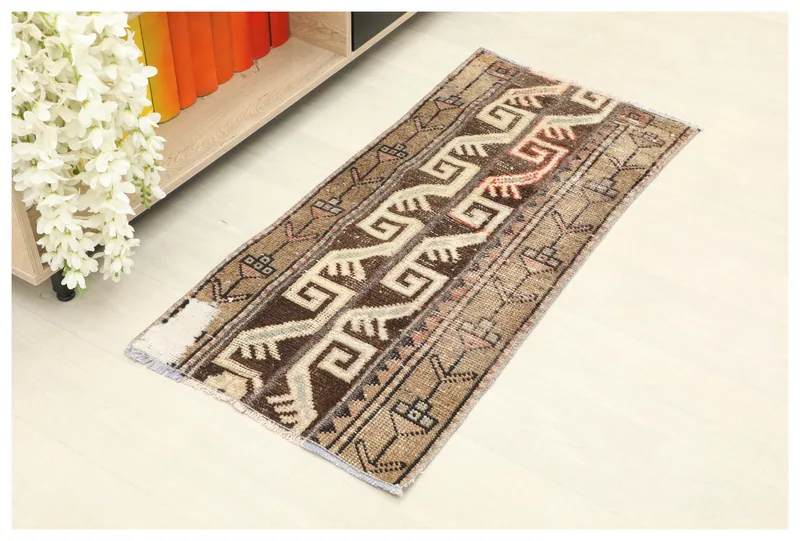 Full top view of the 1'8" x 3'9" brown and tan vintage Anatolian rug on a white floor, showing geometric patterns.