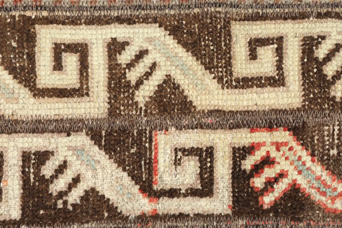 Detailed shot of the central geometric pattern, featuring ivory and brown interlocking shapes and subtle rose accents.