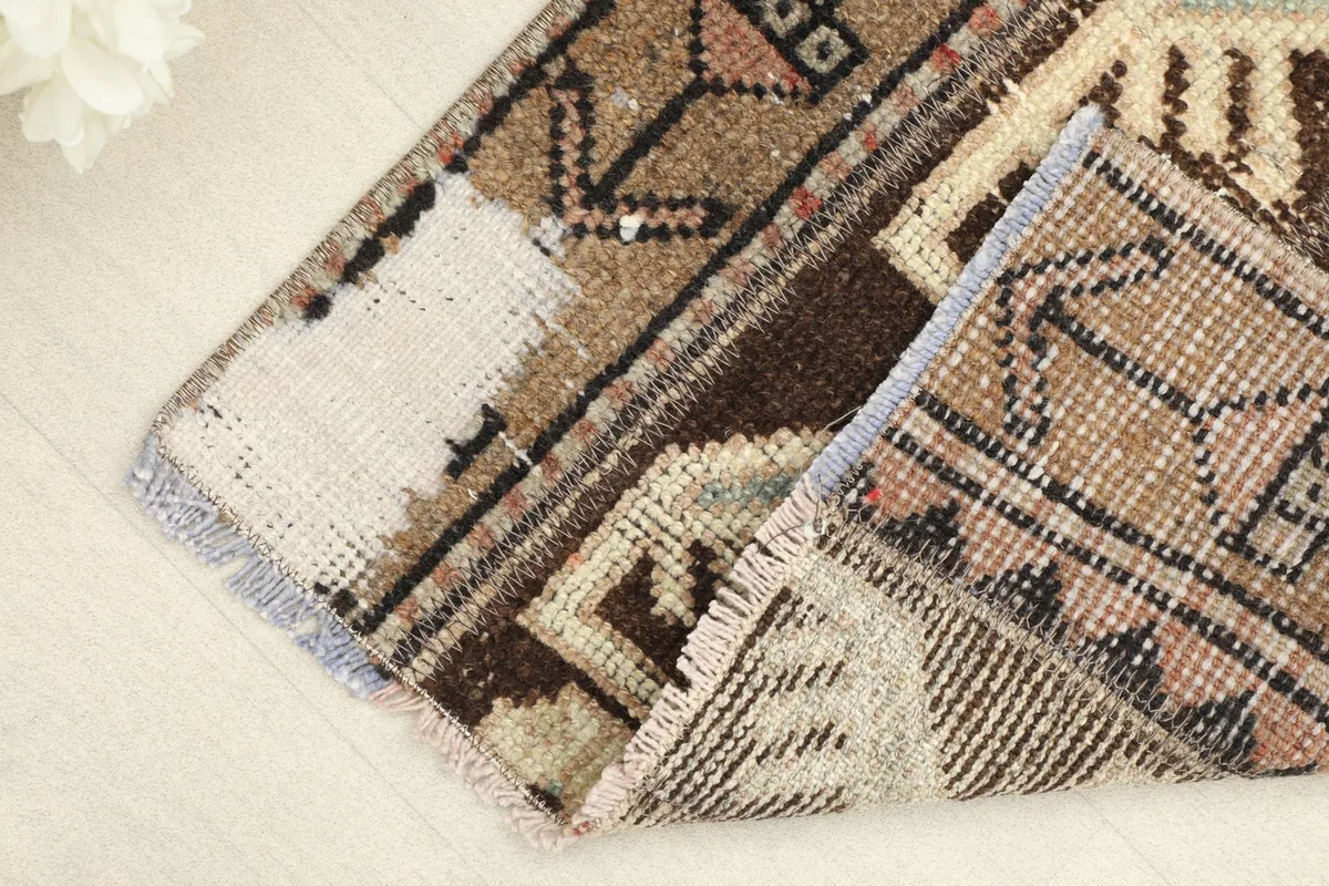 Corner of the rug folded to reveal the cotton foundation and the reverse side of the hand-knotted construction.