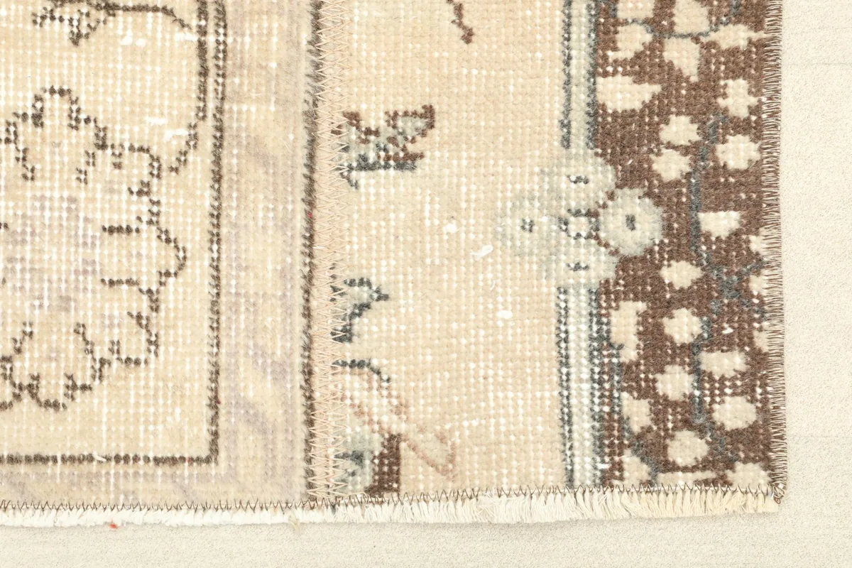 Close-up detail of the rug's short fringe and the transition from the beige field to the brown border.