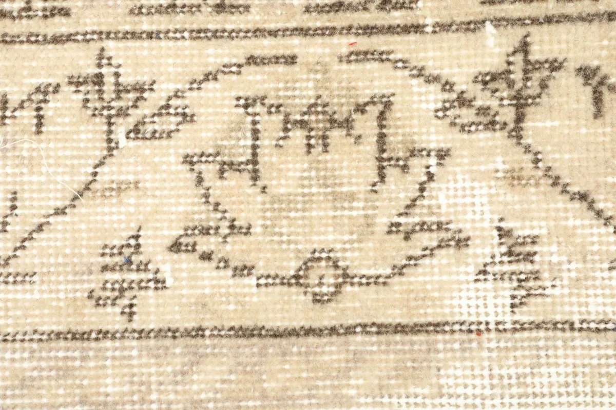 Detailed close-up of the intricate hand-knotted patterns within the rug's beige central design.
