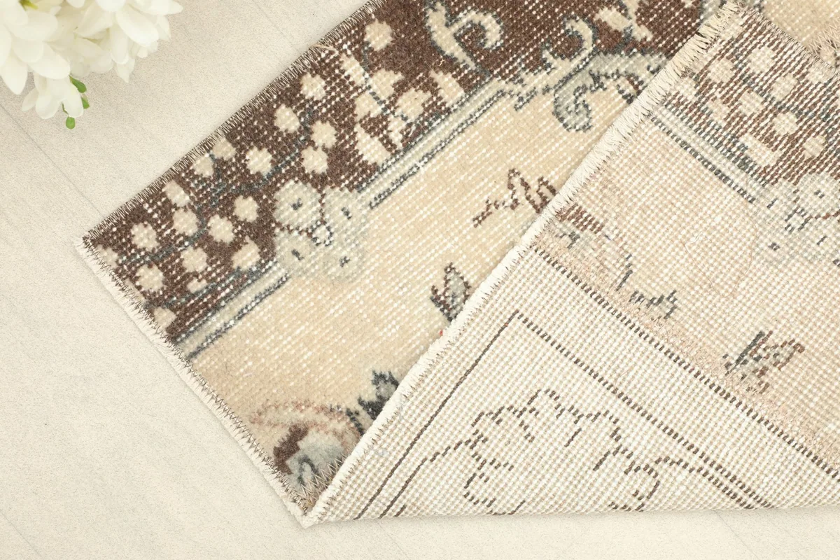 Folded corner of the rug, revealing the wool pile on the front and the cotton foundation on the back.