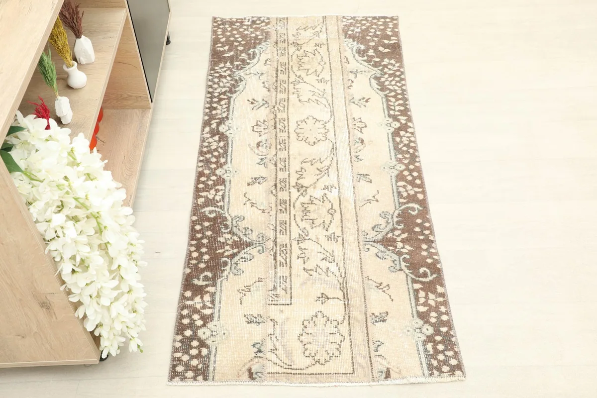 Straight overhead view of the beige field and brown border of the vintage Anatolian rug.