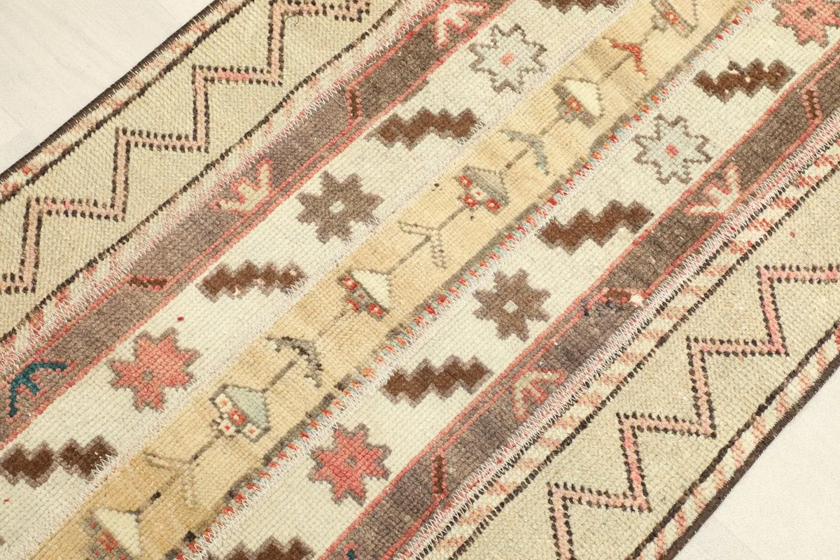 Angled view of the rug's surface, revealing the varied cream, brown, and rust tones in its design.