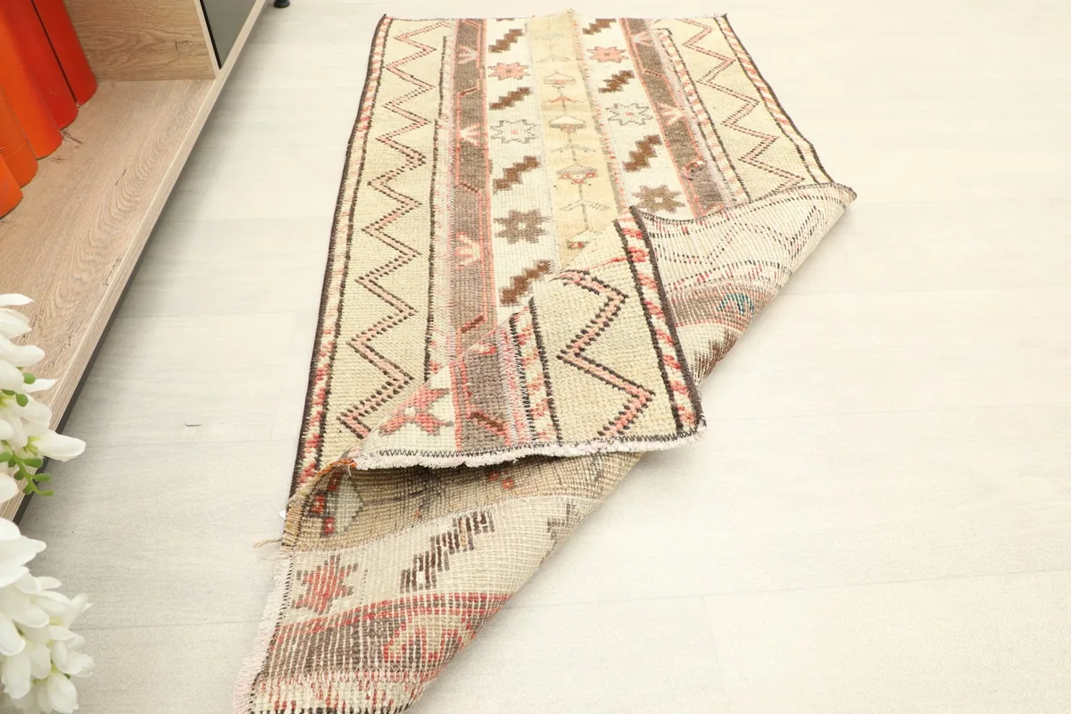The 2'0" x 4'2" rug partially folded in a room setting, next to a shelf with books.