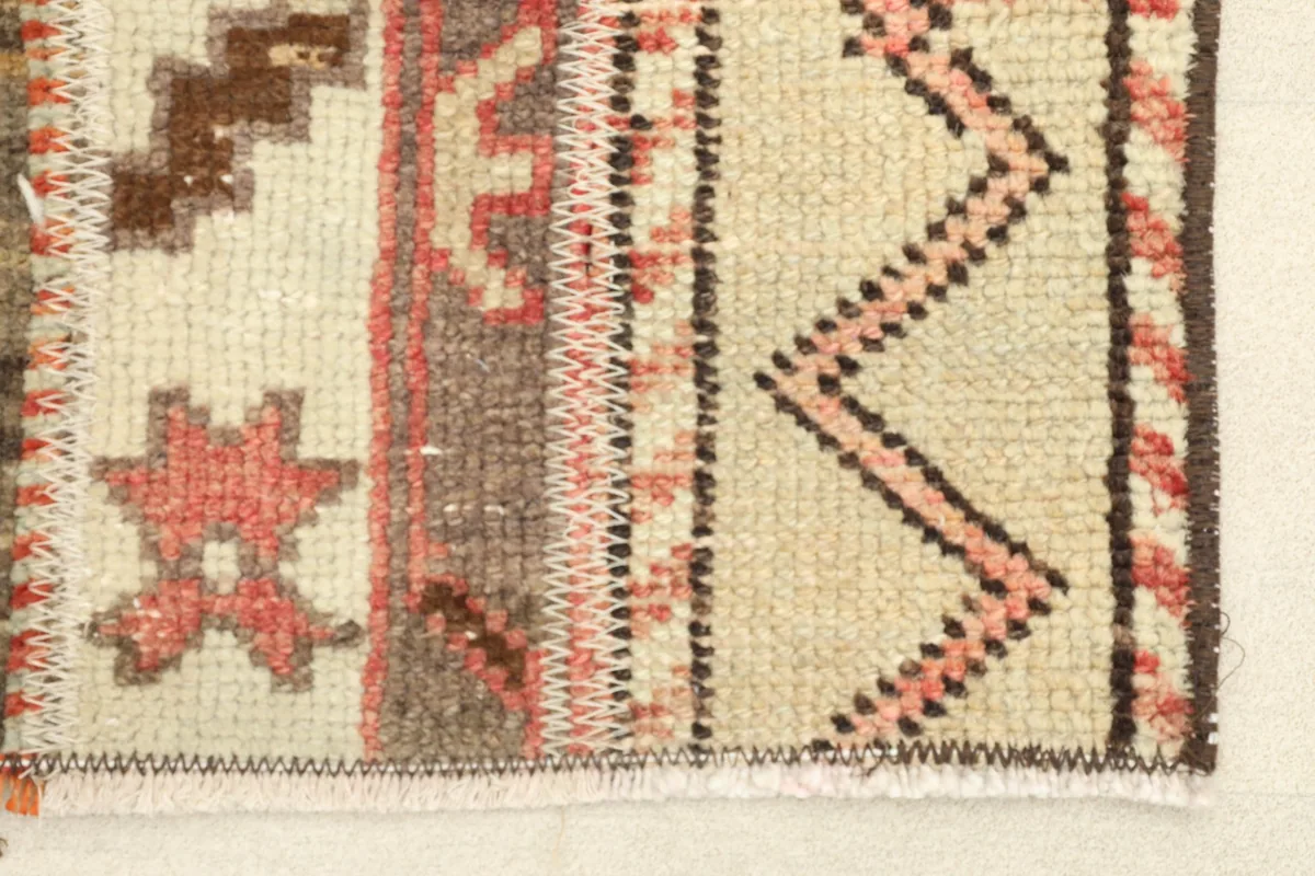 Close-up detail of the rug's edge, showing the hand-knotted pile and zigzag border in rust and brown.