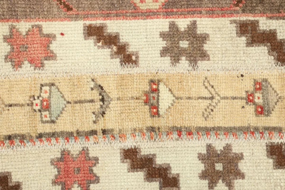 Detailed section of the rug's central motifs, featuring small pink, brown, and gray geometric shapes.