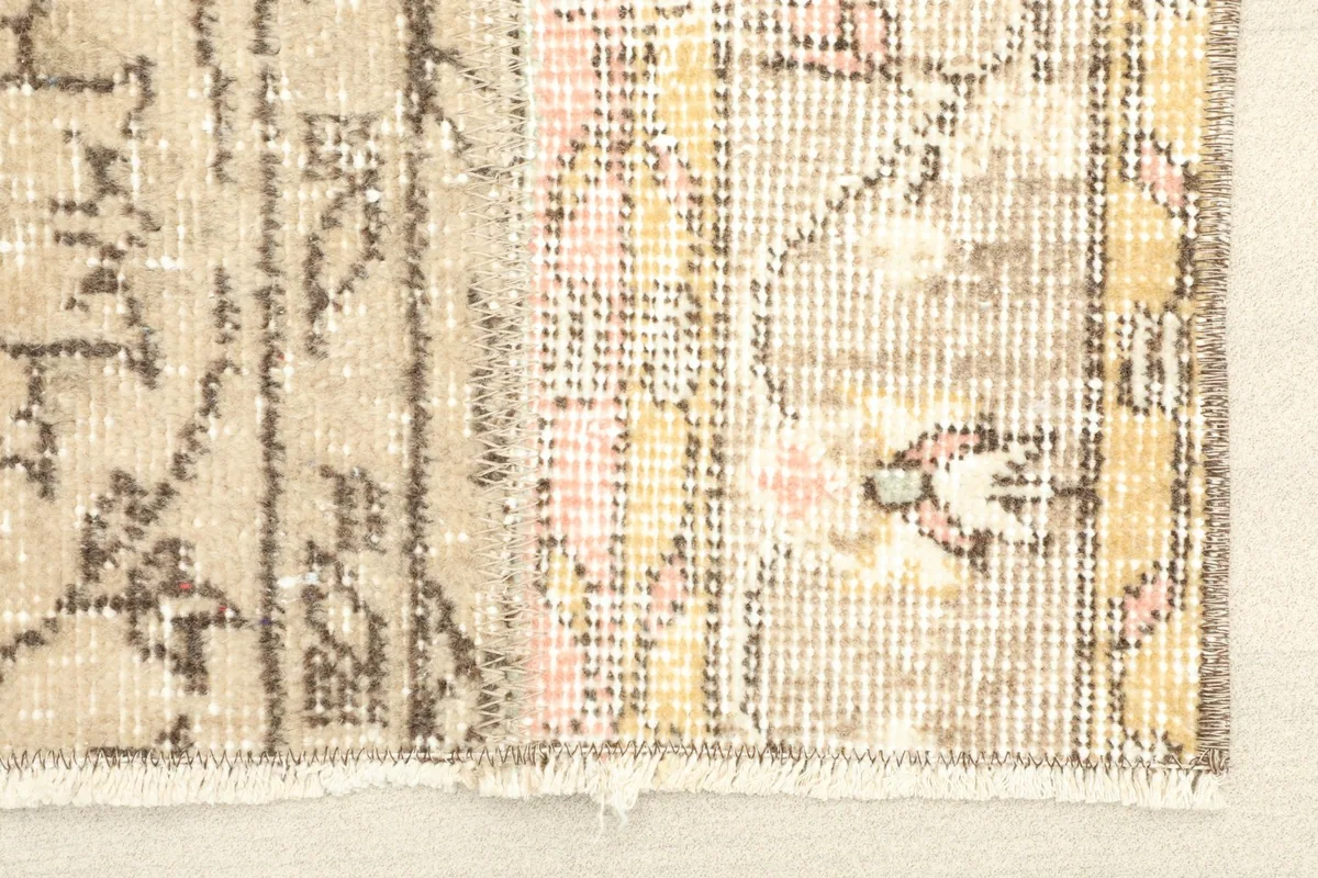 Close-up detail of the rug's patchwork construction, showing different panels and fringe.