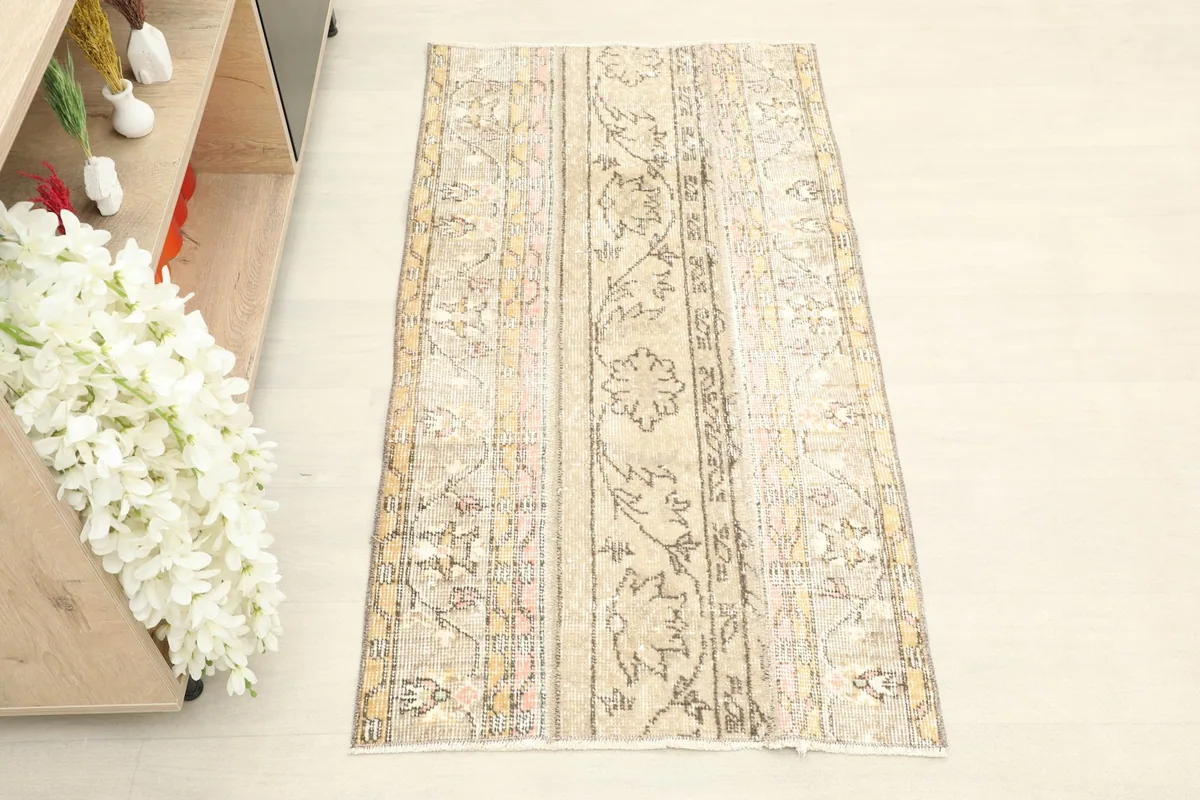 Overhead view of the beige and cream vintage rug, showcasing its full design and color variations.