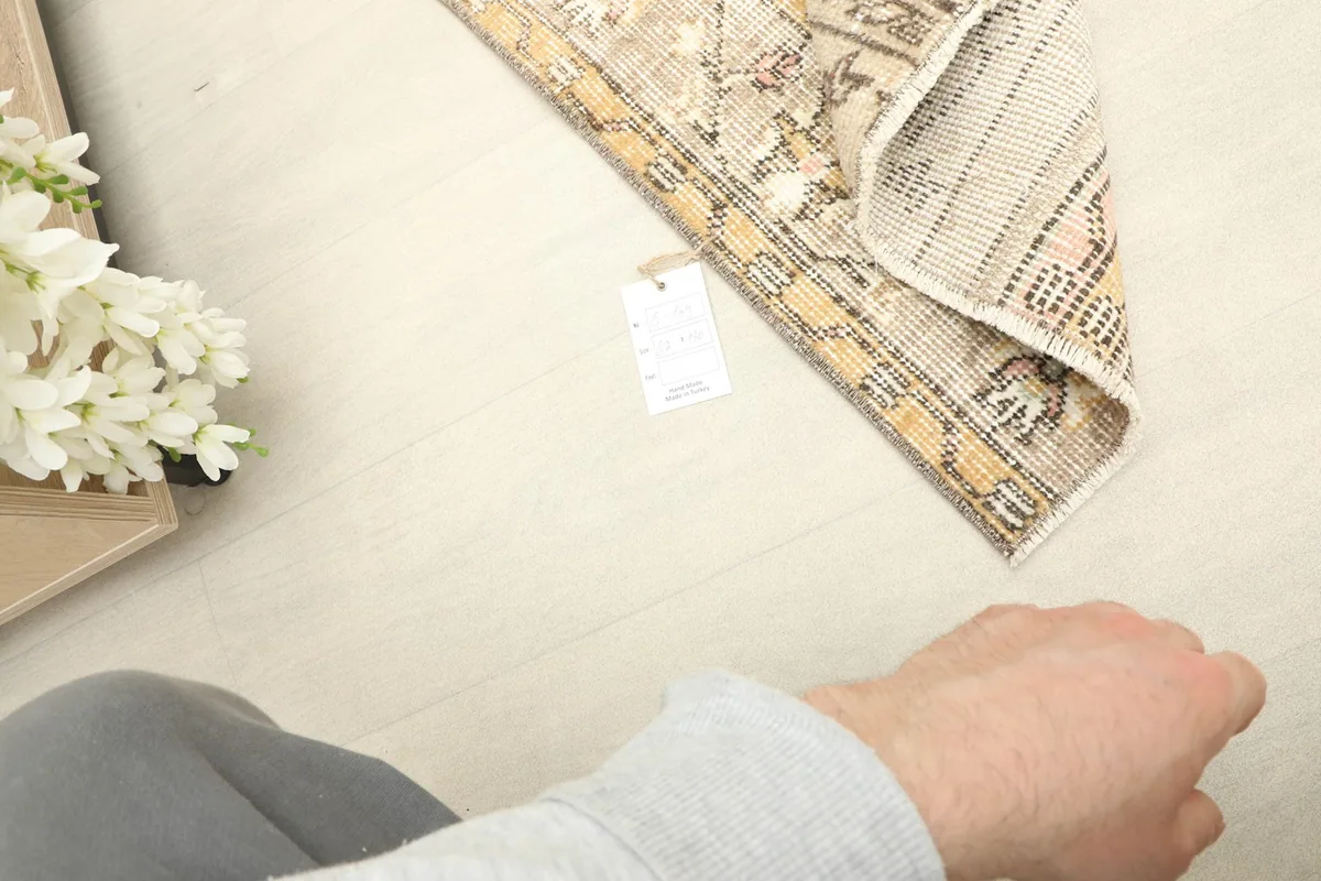 Hand pointing to the rug's tag, indicating its quality and origin details.