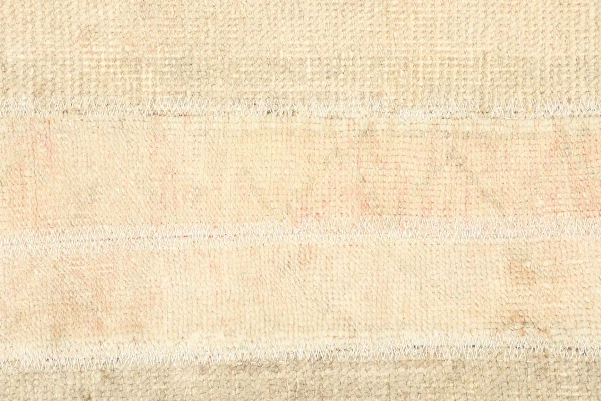 Detailed view of the rug's surface, showing the low pile and texture of the ivory and faded rose wool.