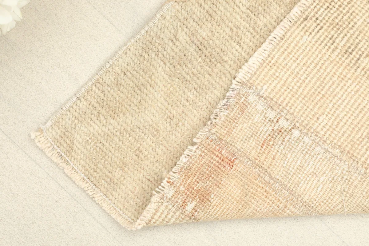 Corner of the rug folded to show the hand-knotted back and the cotton foundation beneath the wool pile.