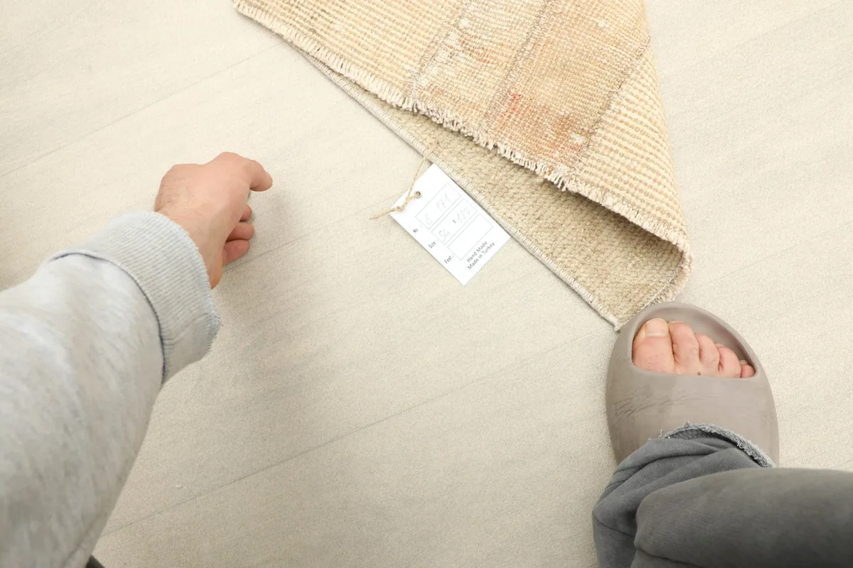Perspective shot of the rug on the floor, indicating its size relative to a person's foot.