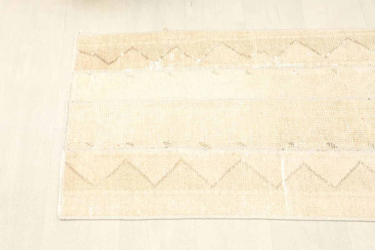Corner view of the rug, illustrating the soft coloration and aged character of the textile.