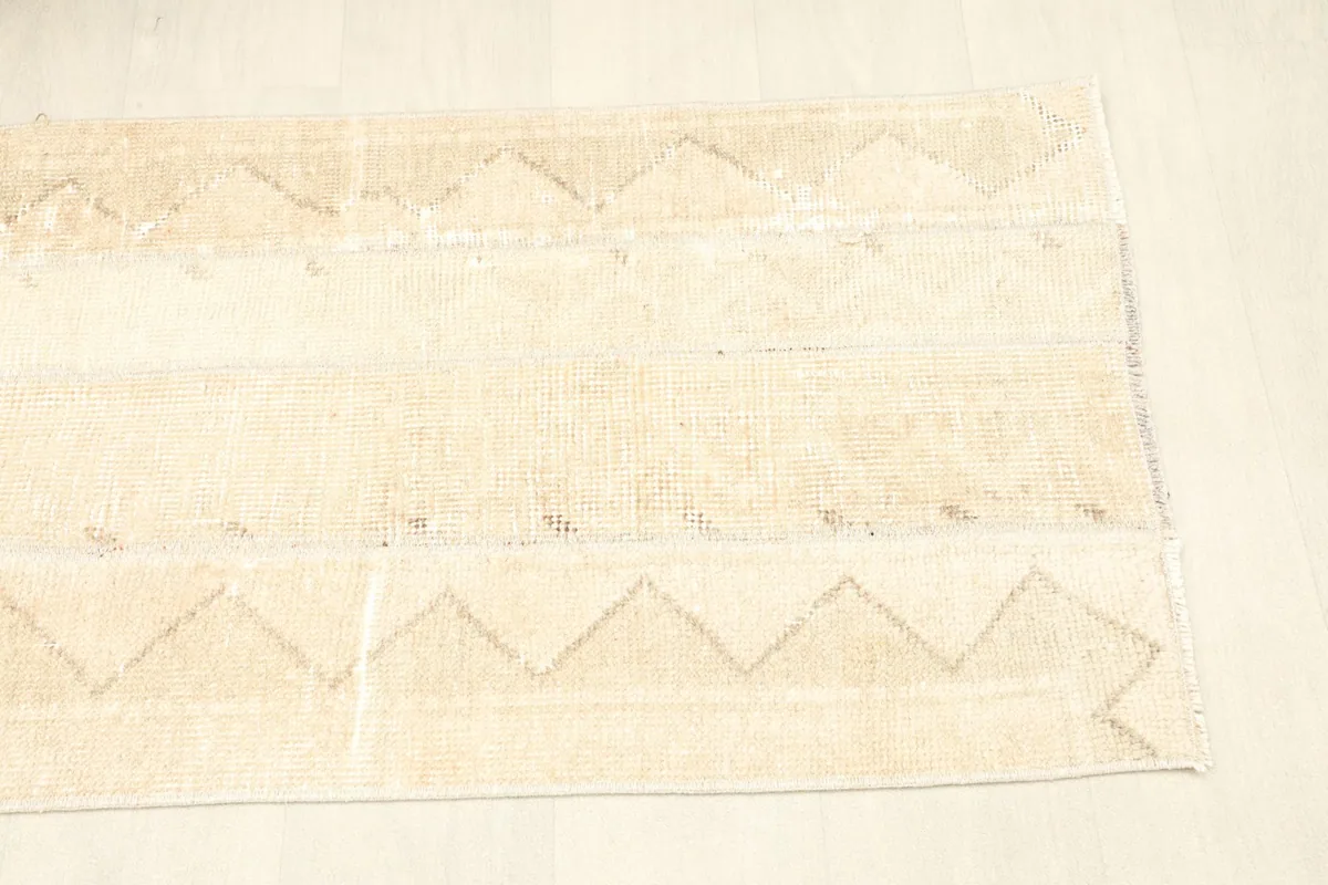 View from the opposite corner, showing the natural light play on the rug's surface and its faded design.