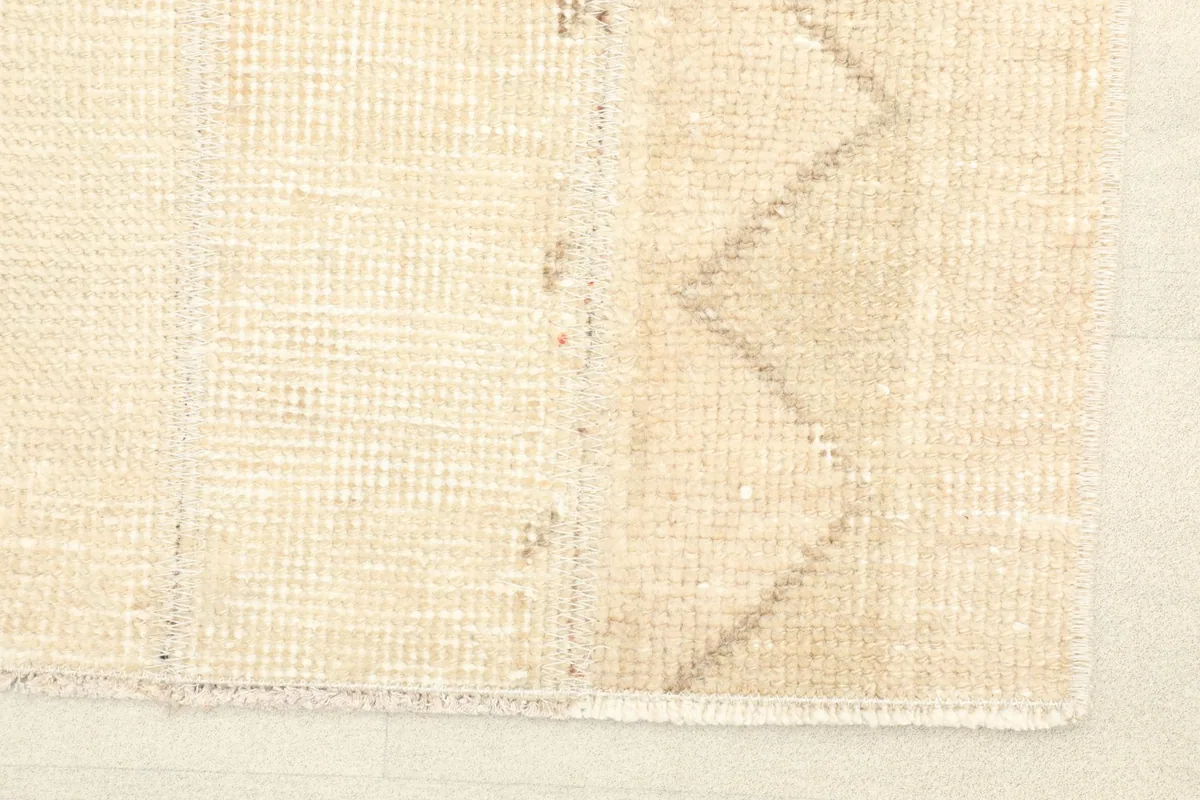 Close-up detail of the rug's texture, showing the subtle geometric lines and variations in the ivory wool pile.