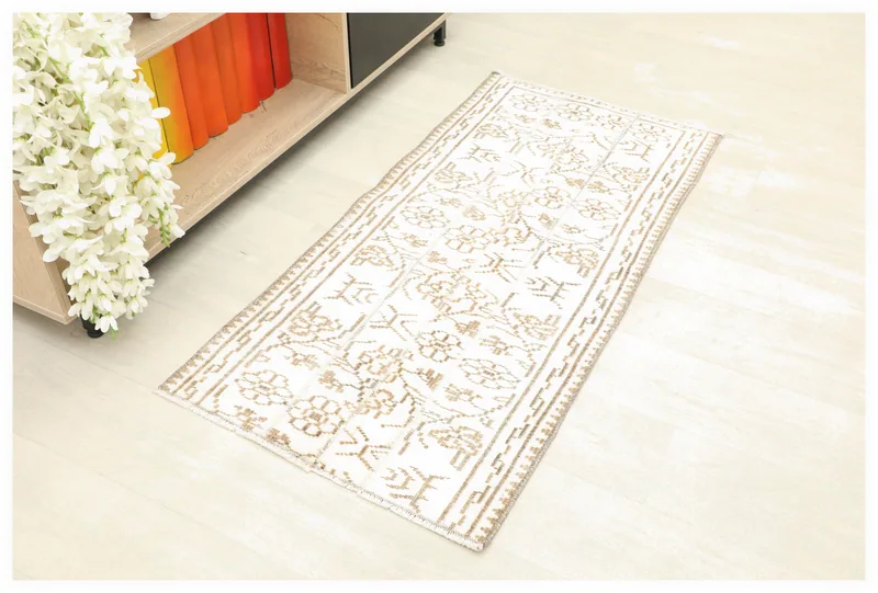 Full overhead view of the ivory and tan floral vintage Anatolian rug on a white background.
