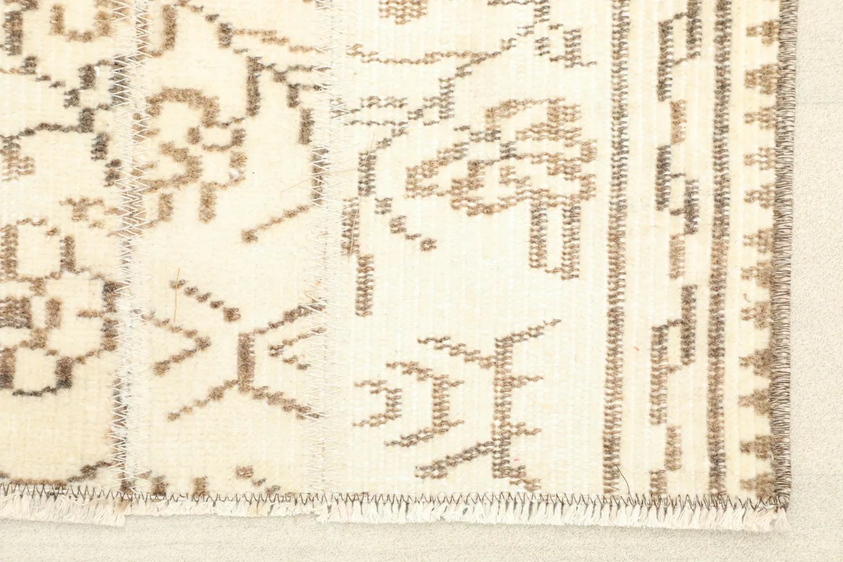 Close-up detail of the rug's short fringe and the intricate tan geometric and floral patterns on an ivory field.