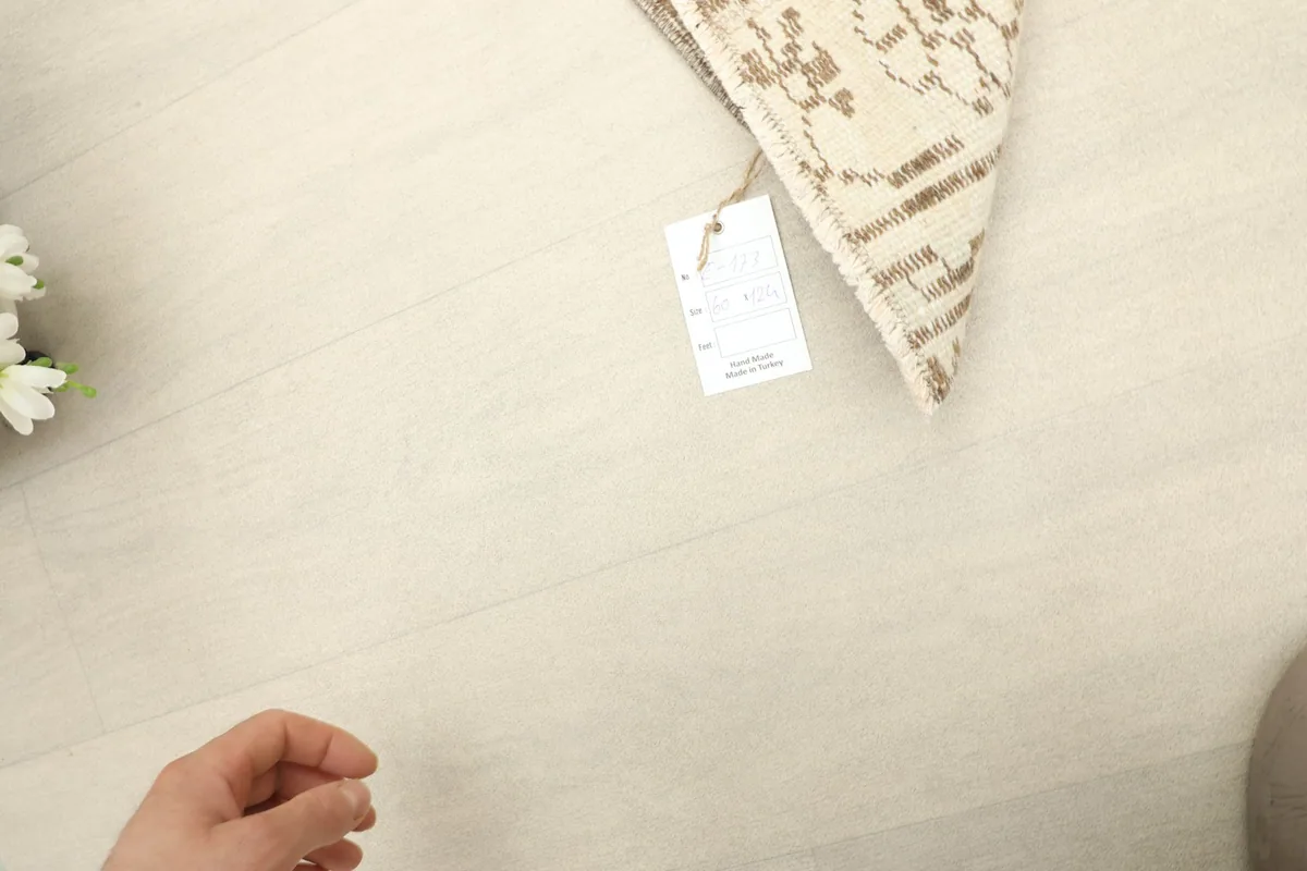 Close-up of the rug's back with a product tag, showing the hand-knotted cotton foundation and wool pile.