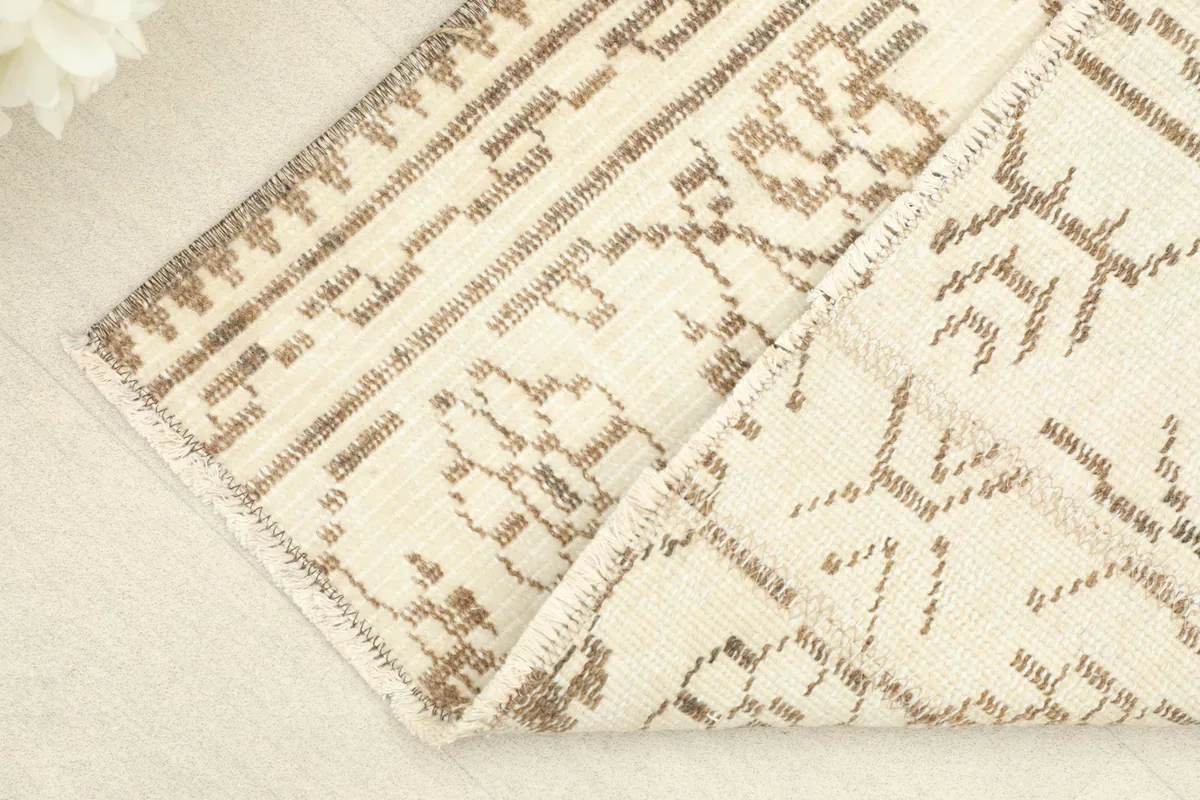 Corner of the rug folded back, revealing the wool pile and cotton foundation, showing the rug's construction.