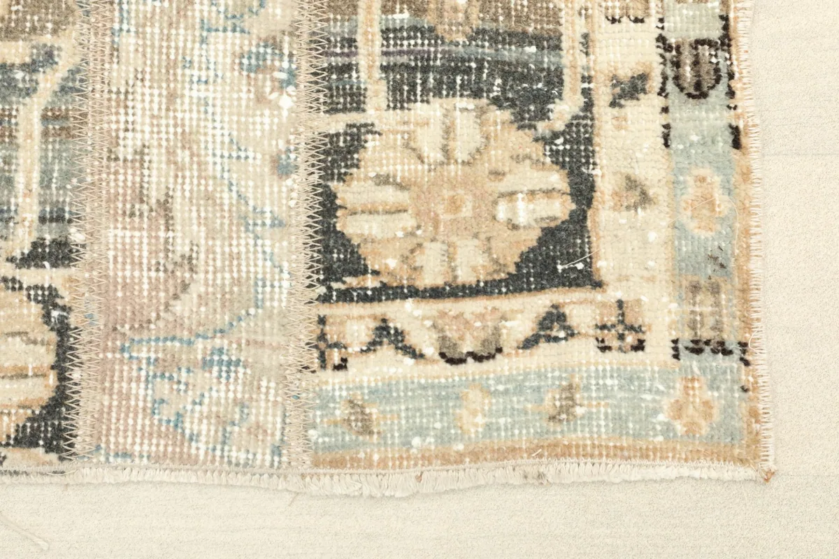 Close-up detail of the rug's corner, highlighting the patchwork seams and geometric motifs in blue and black.