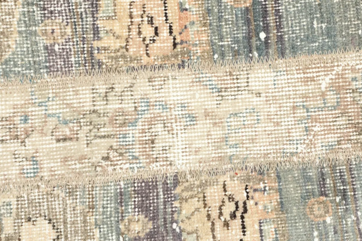 Detailed view of the central patchwork seam and faded patterns on the Anatolian wool rug.