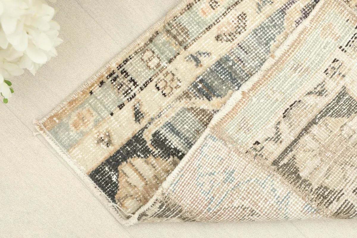 Corner of the rug folded back, revealing the wool pile and cotton foundation construction.