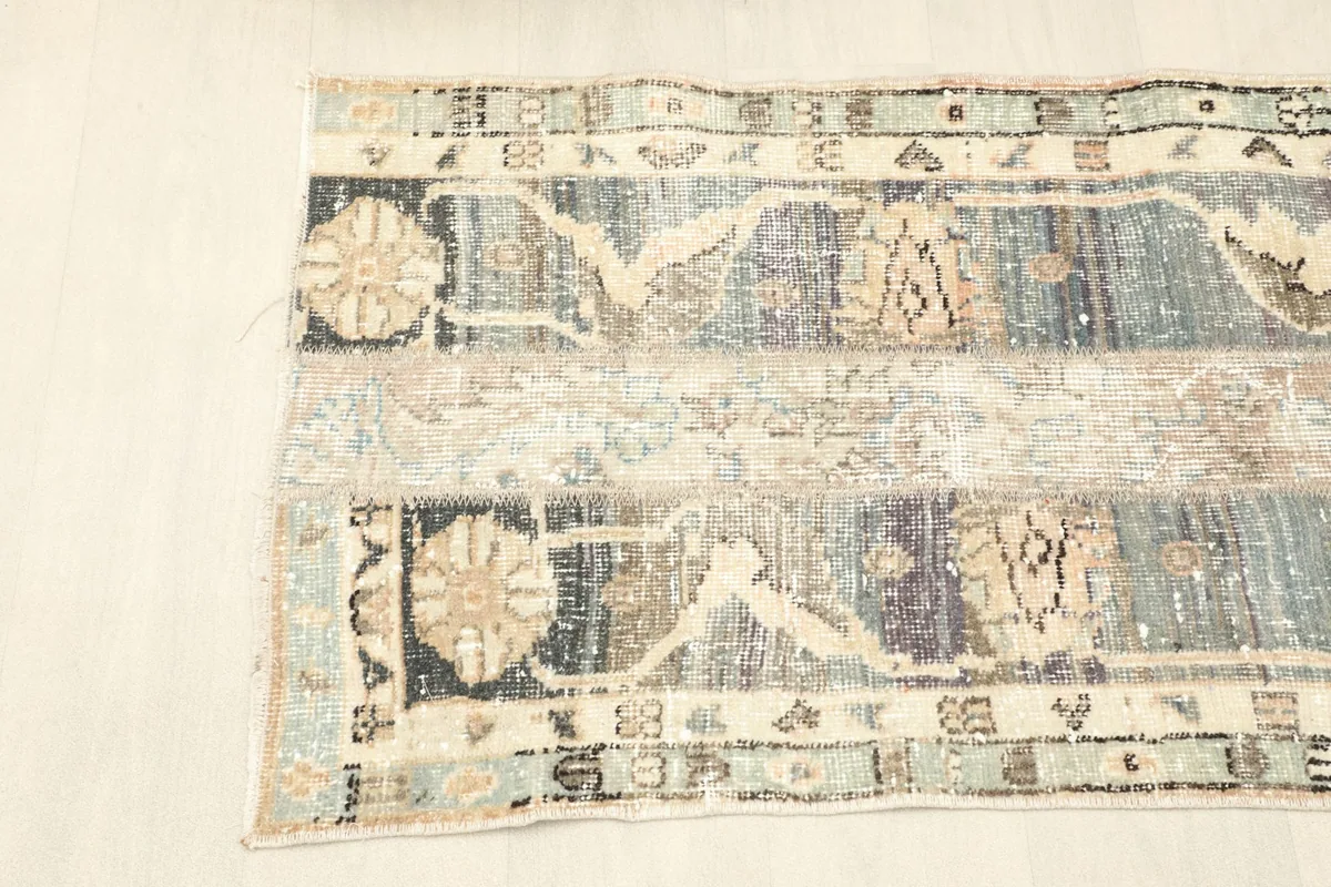 Half overhead view of the rug, illustrating the distinct sections of the blue and tan patchwork design.