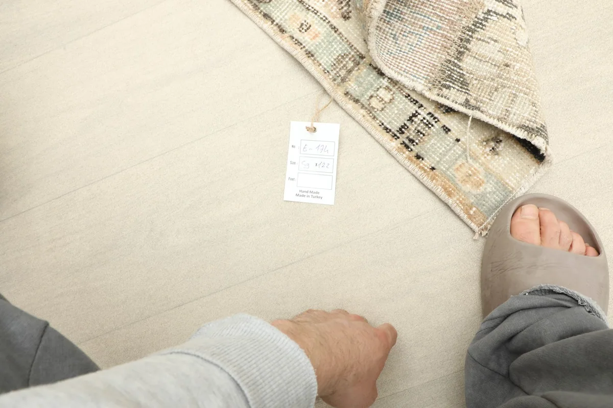 View from above showing a foot next to the folded rug, indicating its mini size and texture.