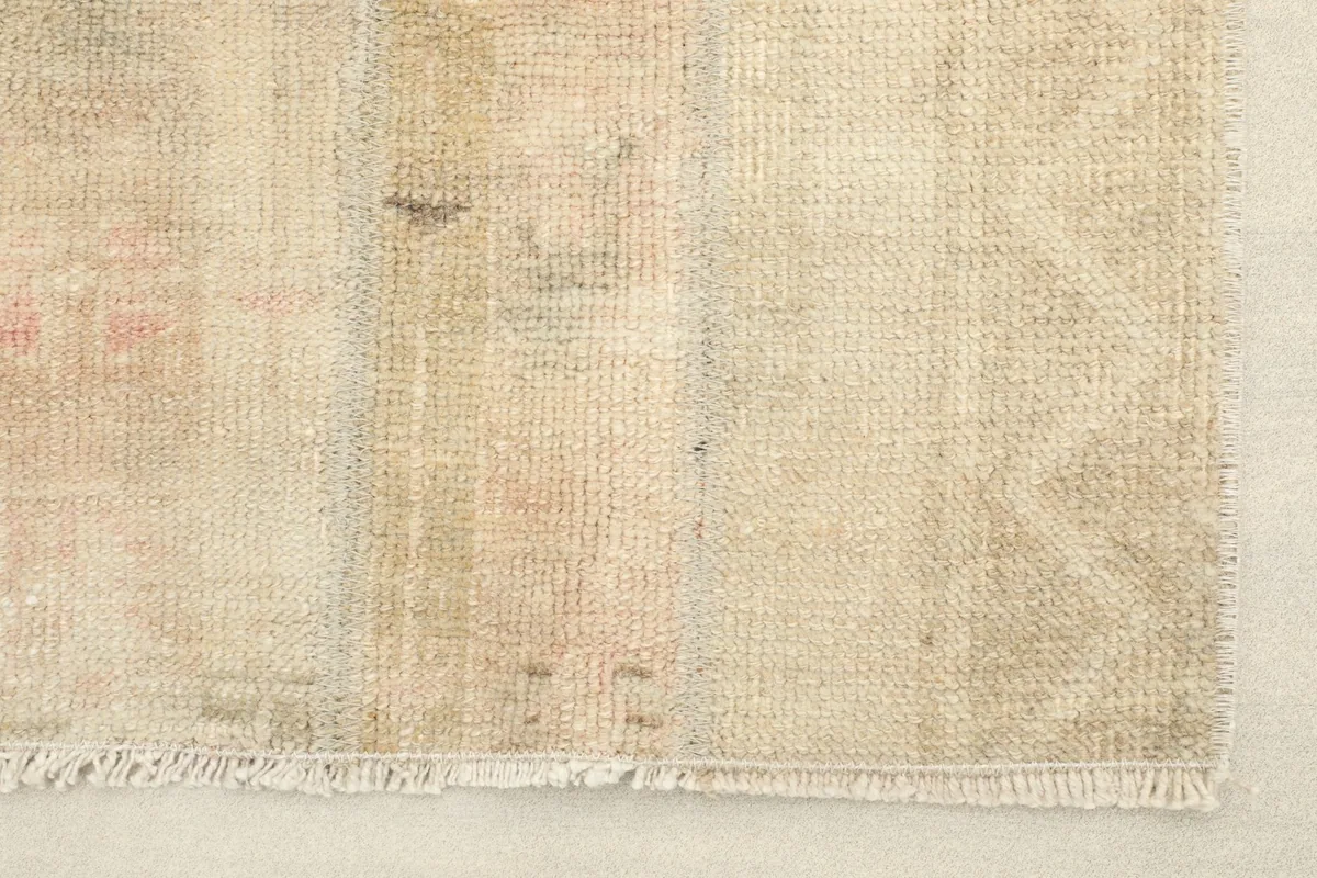 Close-up detail of the rug's texture and subtle rose and cream tones near the edge