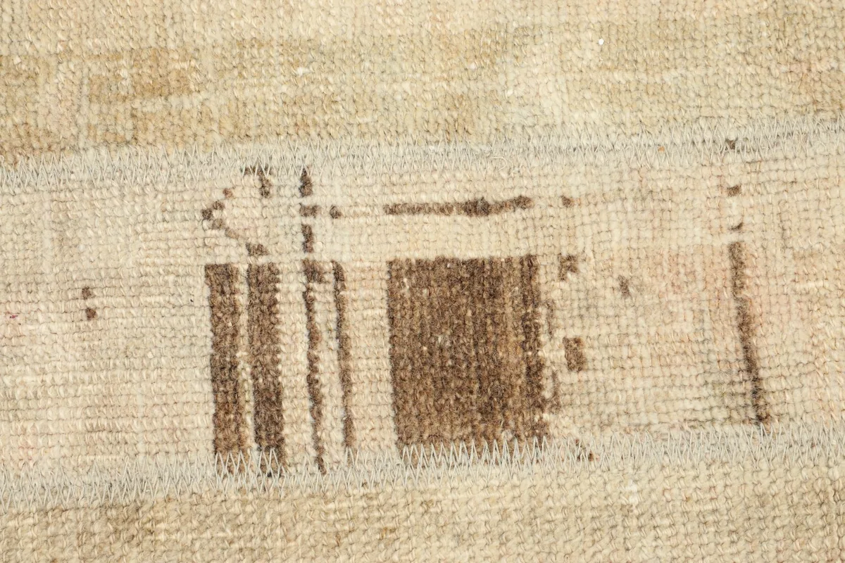 Detailed shot of the central abstract brown pattern on the beige wool pile