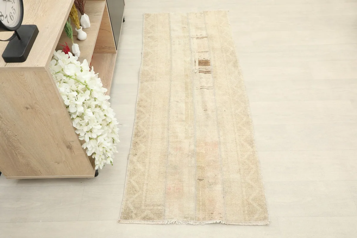 Overhead view of the beige runner rug, showcasing its full length and faded patterns