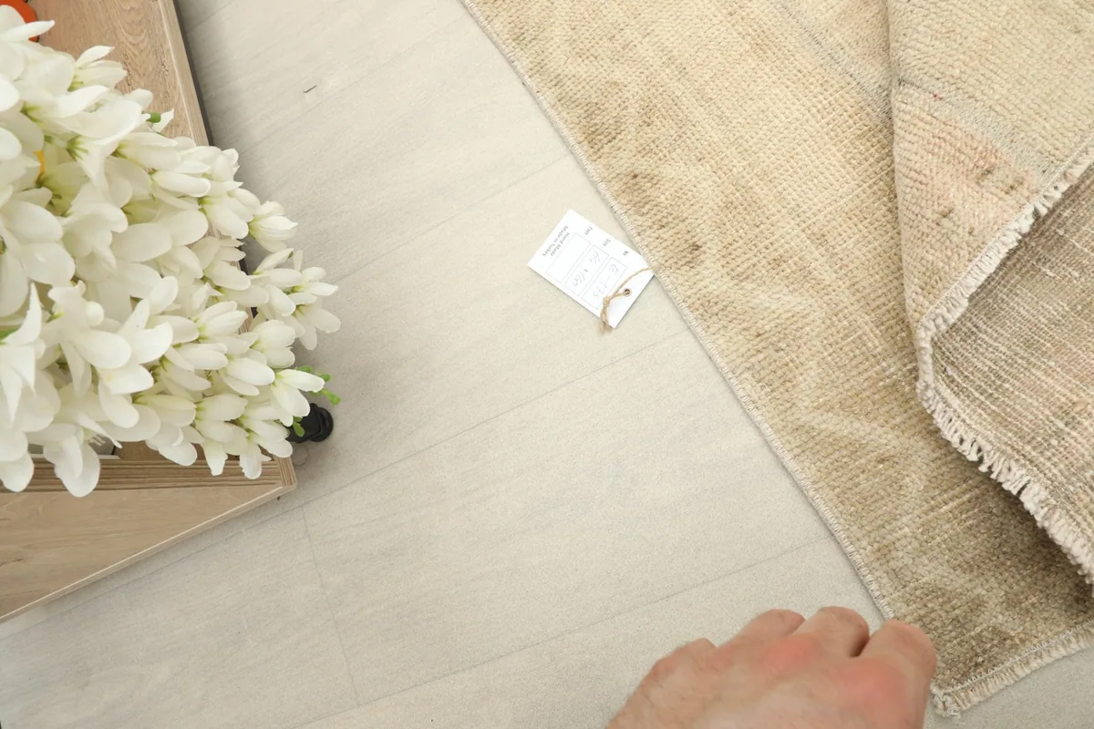 Hand touching the rug, illustrating its soft texture and scale next to a decorative item