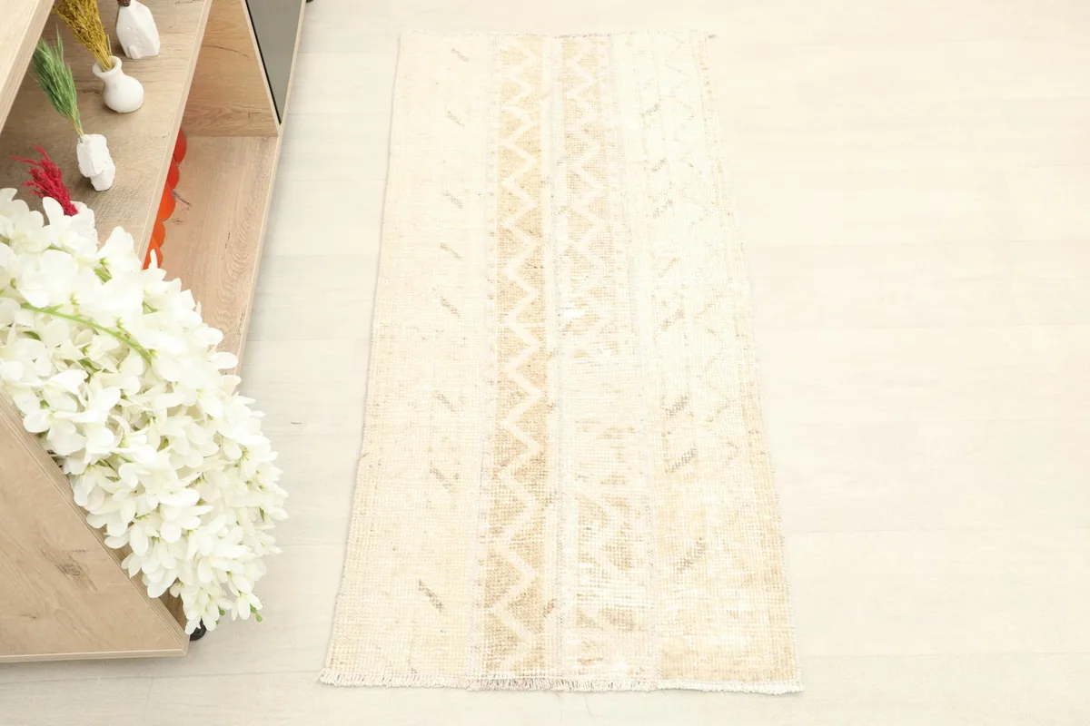 Overhead view of the ivory and beige hand-knotted rug, showing its full length and width.
