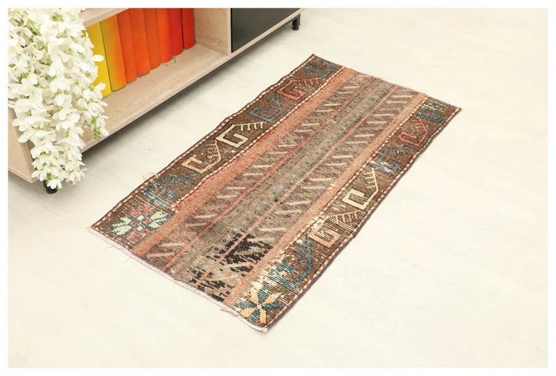 Full top view of the brown and rust geometric tribal rug on a white background.