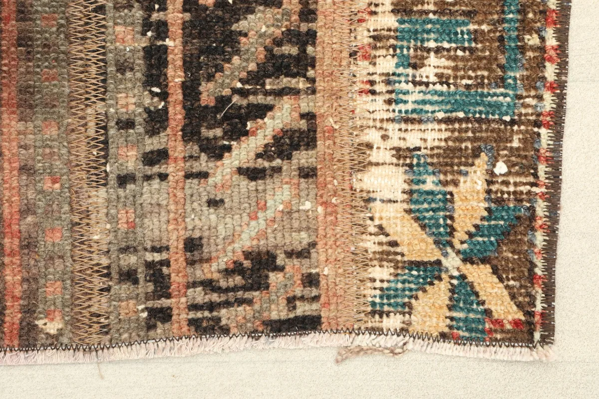 Close-up detail of the rug's texture and patterns, showing areas of wear and color variation.