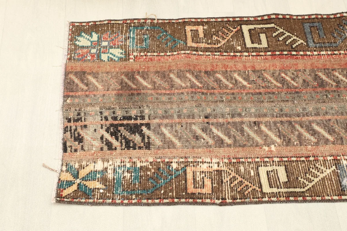 Close-up of the rug's side, featuring tribal patterns in brown, beige, and touches of blue and green.