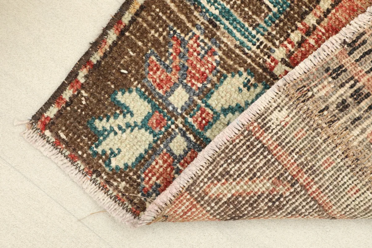 View of the rug's underside and corner, revealing the hand-knotted cotton foundation and wool pile.