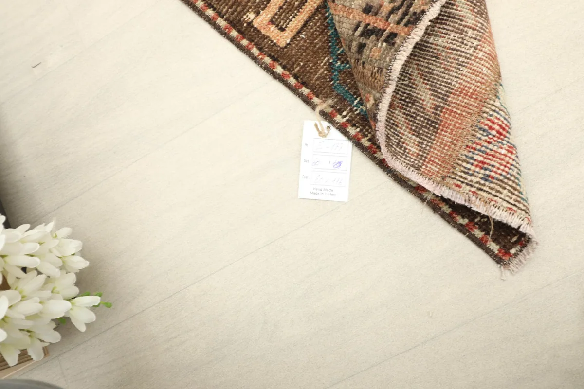 Corner of the rug with a tag, showing the reverse side and the hand-knotted construction.