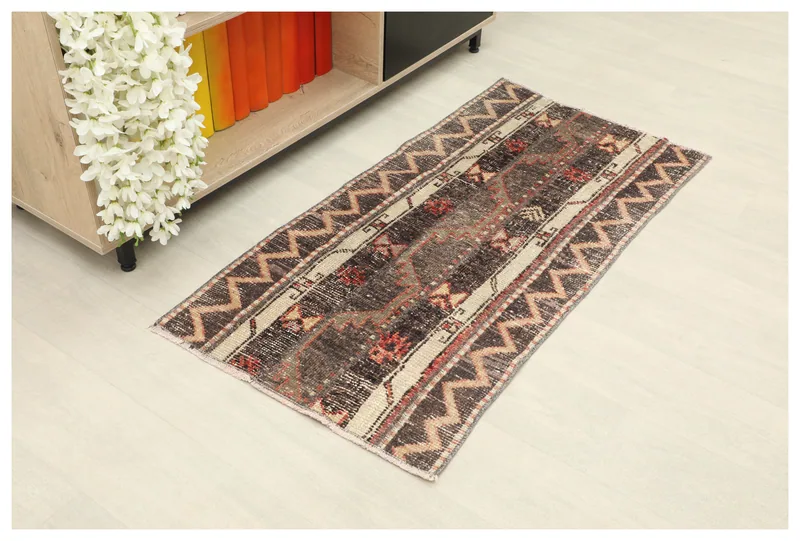 Full top view of the vintage Anatolian rug with charcoal, beige, and red tribal patterns