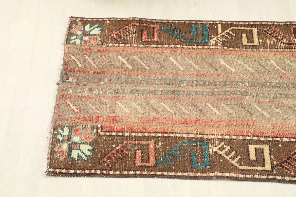 Side view of the rug, focusing on the brown border with its distinctive geometric and tribal designs.