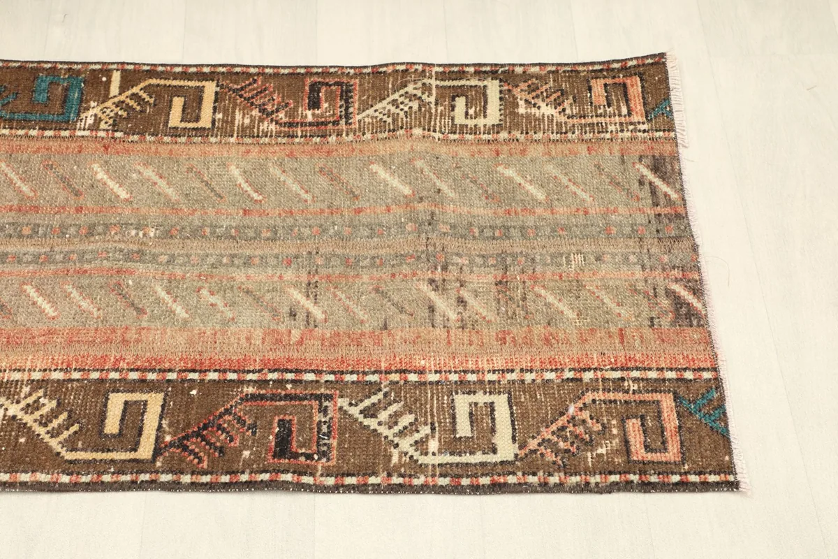 View of the opposite side of the rug, showing the consistent brown border and beige field patterns.