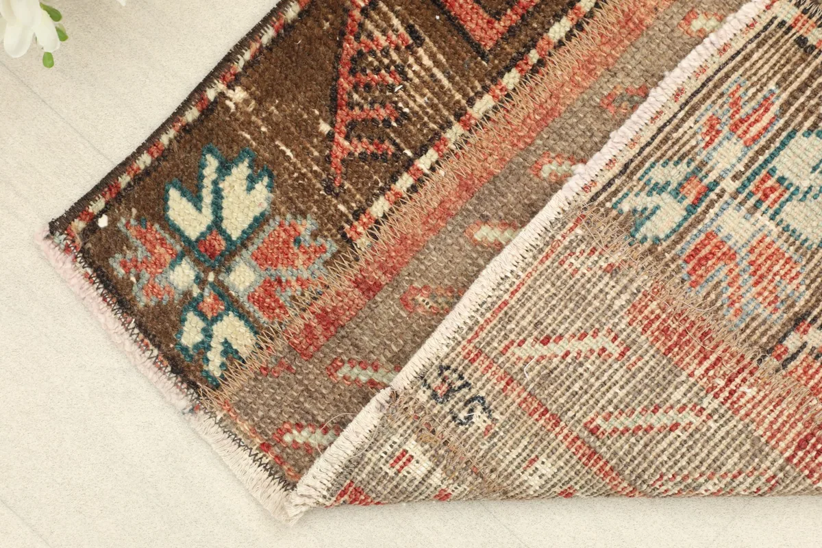 View of the rug's back and folded edge, revealing the hand-knotted cotton foundation and wool pile.